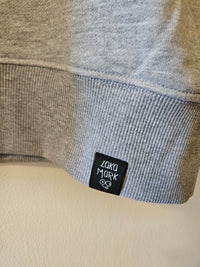 Close-up of grey sweatshirt's ribbed hem with a black Laka Mark label