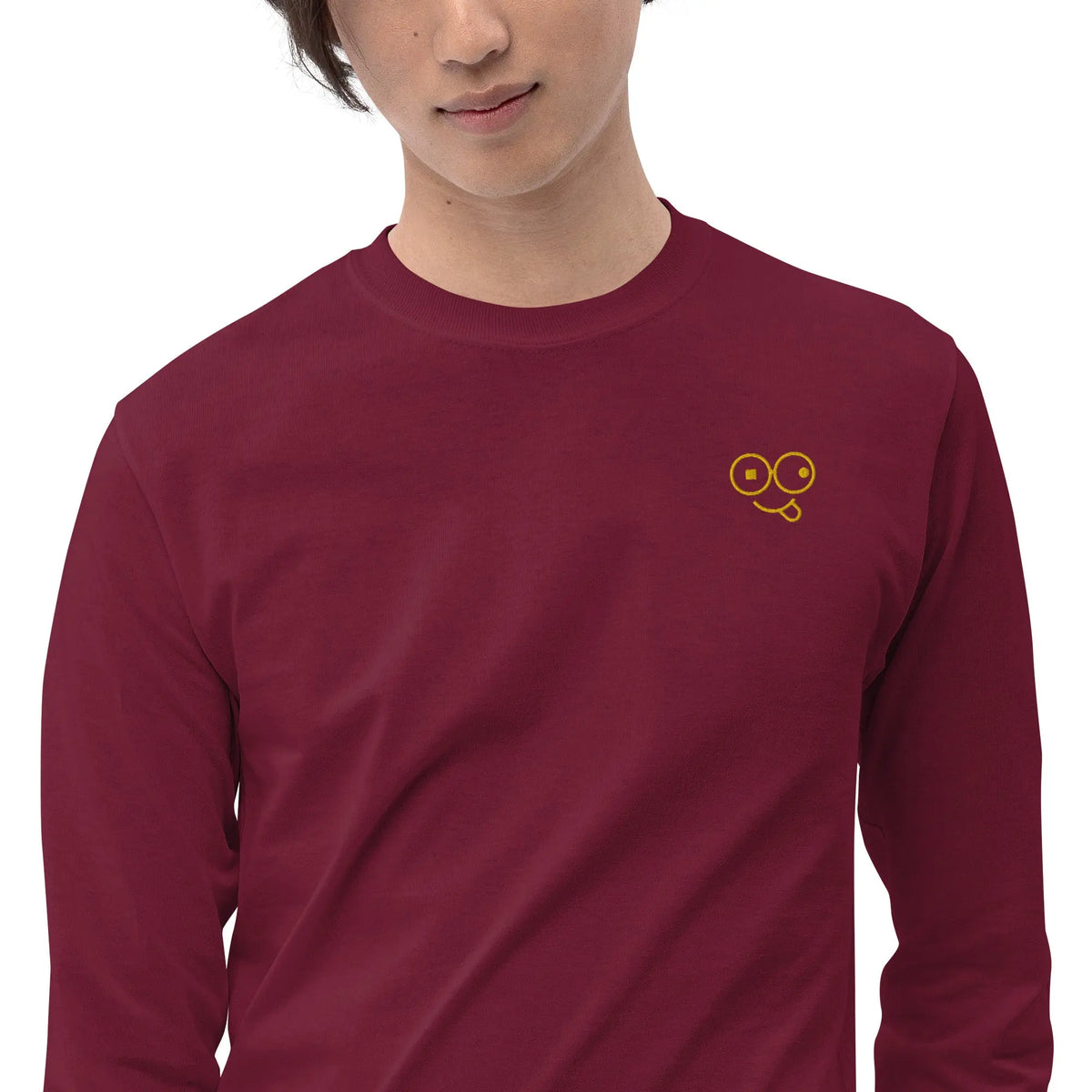 Close-up of a maroon crew neck t-shirt showing the yellow tongue-out glasses-face chest design
