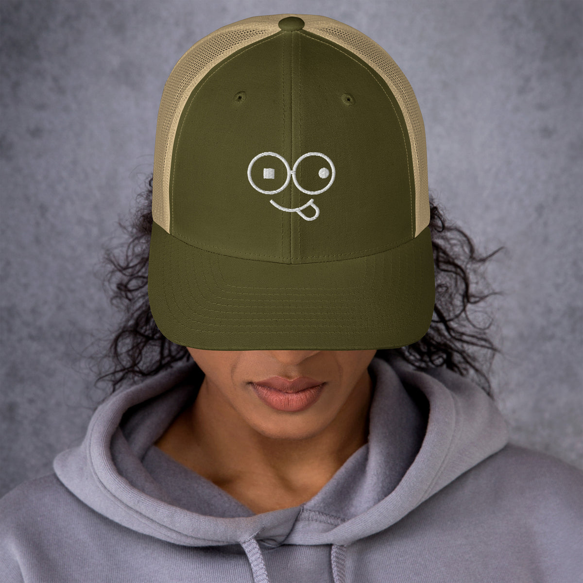 Seated model wearing a navy crew neck t-shirt with a small white tongue-out glasses-face chest design