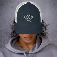 Model wearing a navy trucker hat with white mesh panels and a white tongue-out glasses-face design