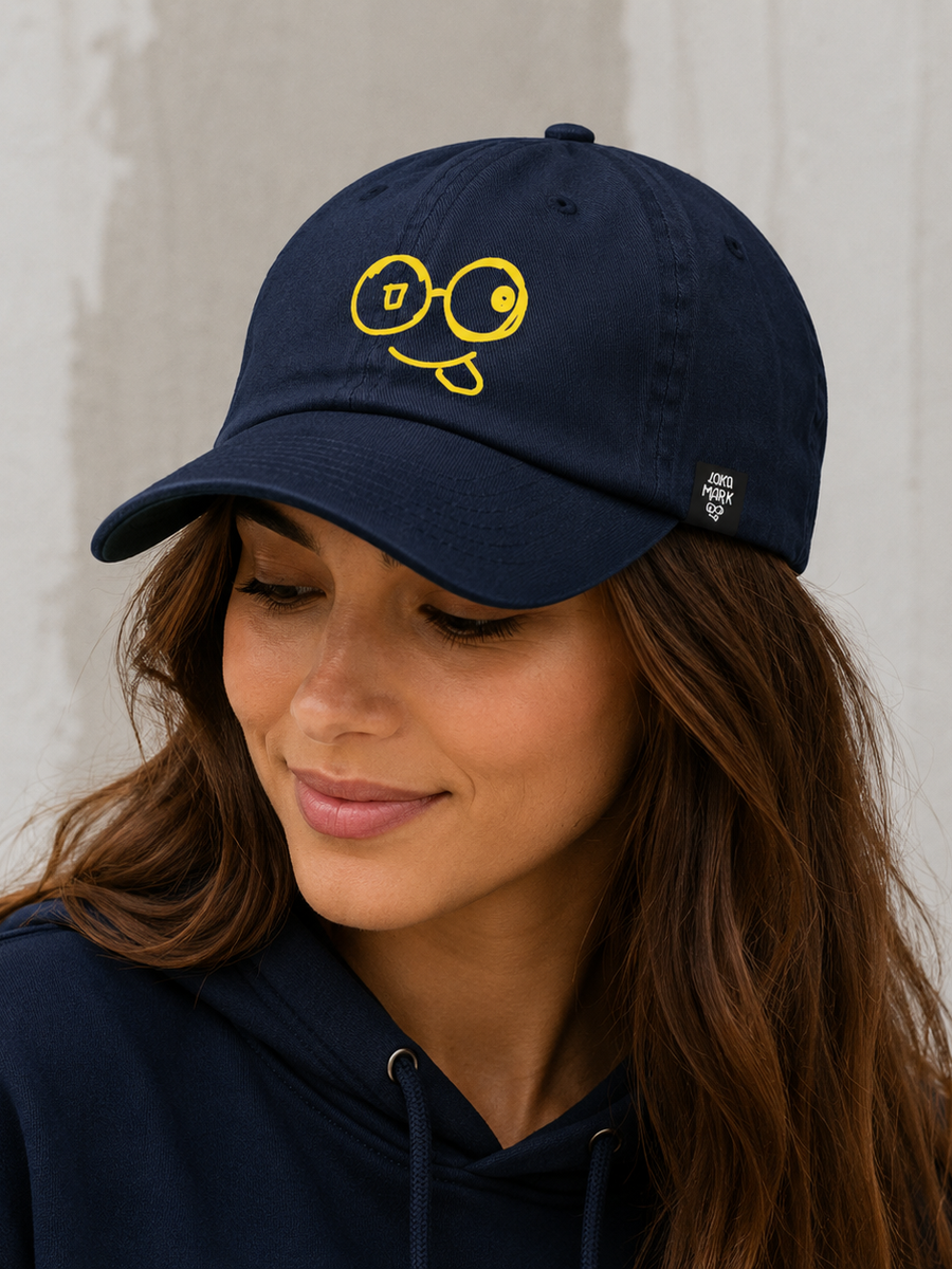 Model wearing a navy dad hat with a yellow glasses-face logo, curved brim and small Laka Mark side label