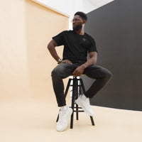 Model seated on a stool wearing a black short sleeve t-shirt with a white glasses-face chest design