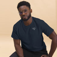 Seated model wearing a navy crew neck t-shirt with a small white tongue-out glasses-face chest design