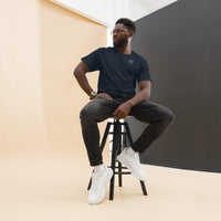 Model seated on a stool wearing a navy short sleeve t-shirt with a white glasses-face chest design