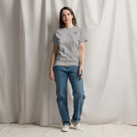 Model wearing a sport grey crew neck t-shirt with a small black glasses-face chest design and blue jeans