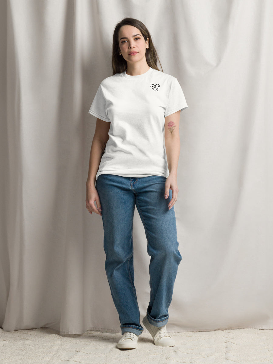 Model wearing a white crew neck t-shirt with a small black glasses-face chest design and blue jeans