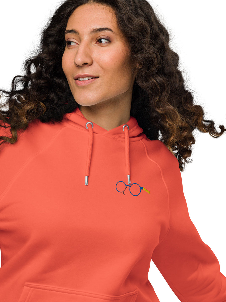 Close-up of orange raglan hoodie showing glasses chest graphic, metal eyelets and drawstring tips