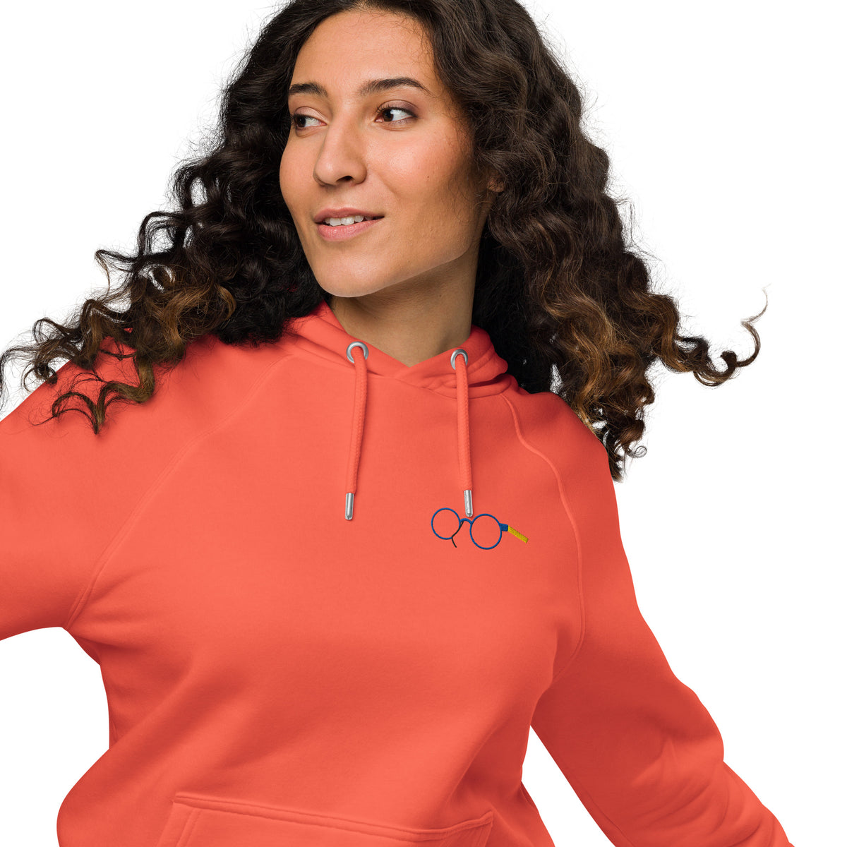 Close-up of orange raglan hoodie showing glasses chest graphic, metal eyelets and drawstring tips