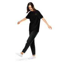 Model wearing a black relaxed-fit unisex t-shirt with a small yellow glasses-face chest design
