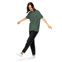 Model wearing a blue spruce green unisex t-shirt with a small yellow glasses-face chest design