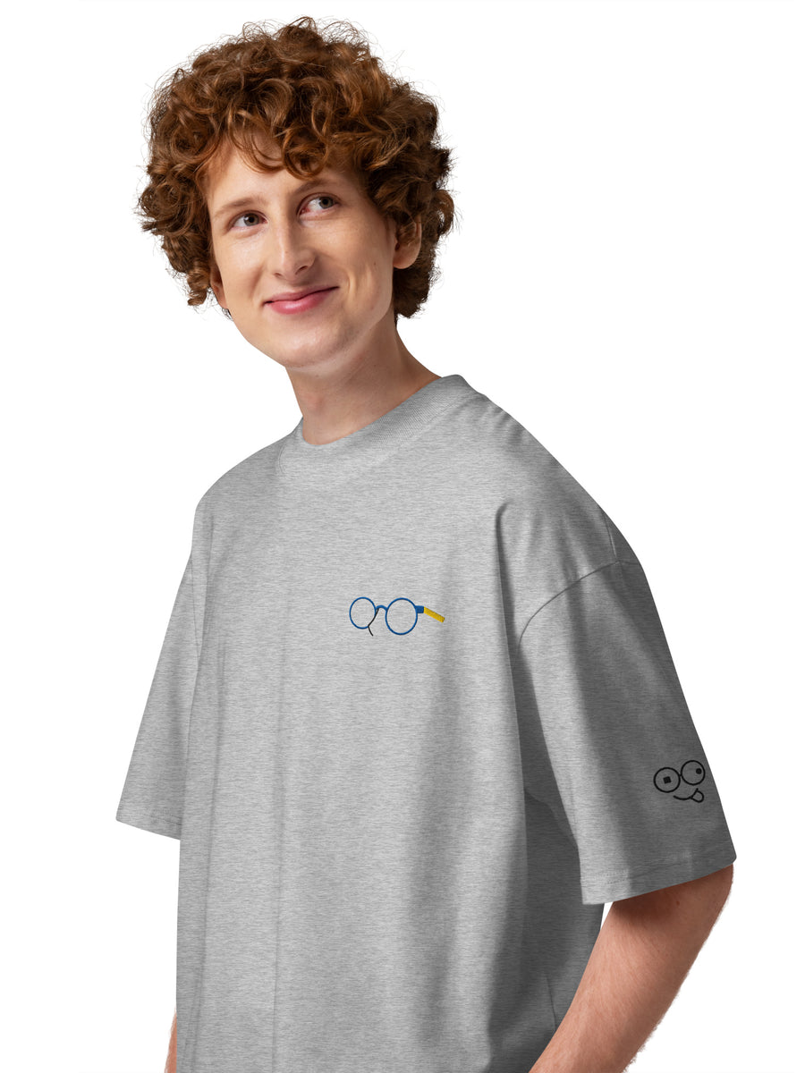 Angled view of heather grey oversized t-shirt showing glasses chest graphic and glasses-face sleeve design