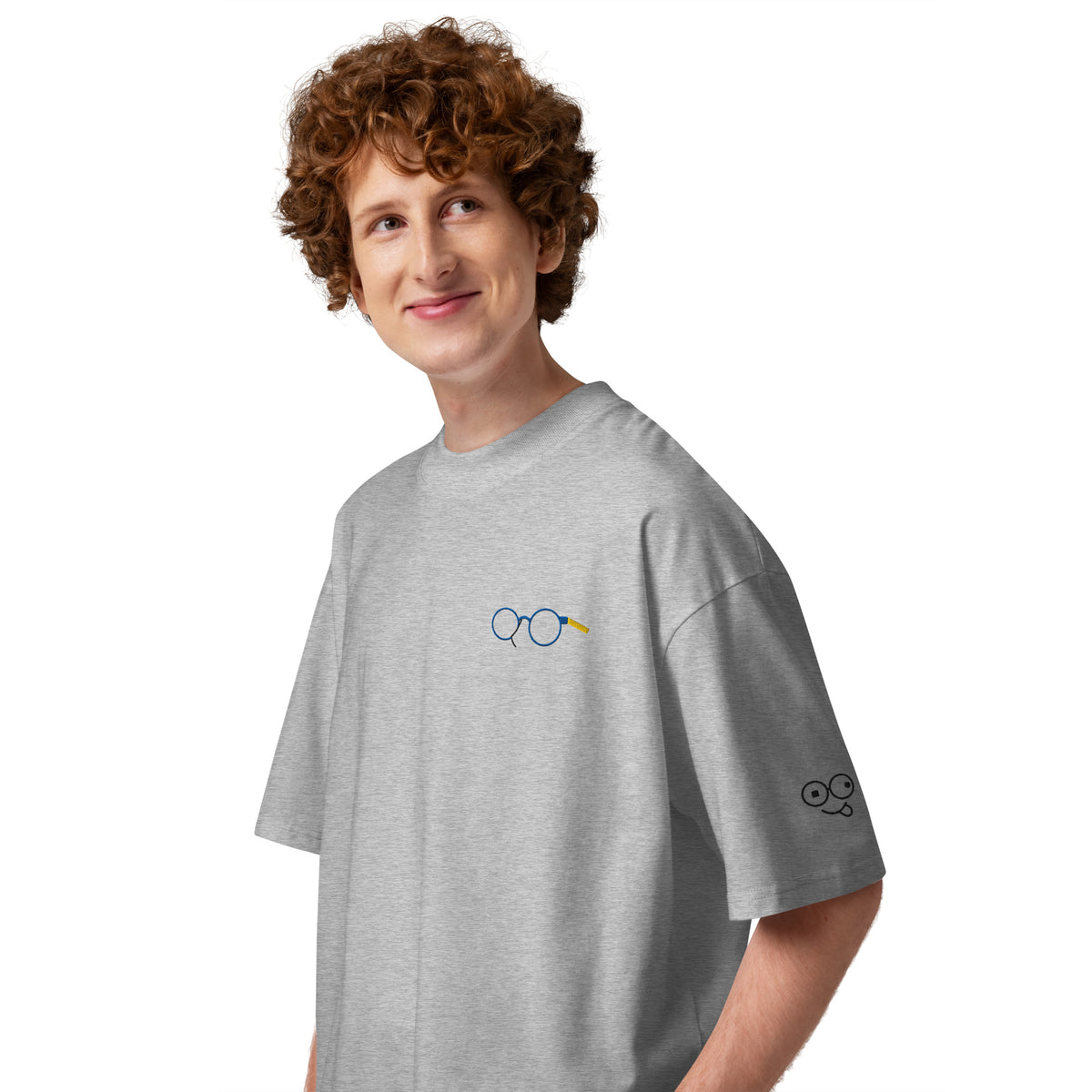 Angled view of heather grey oversized t-shirt showing glasses chest graphic and glasses-face sleeve design