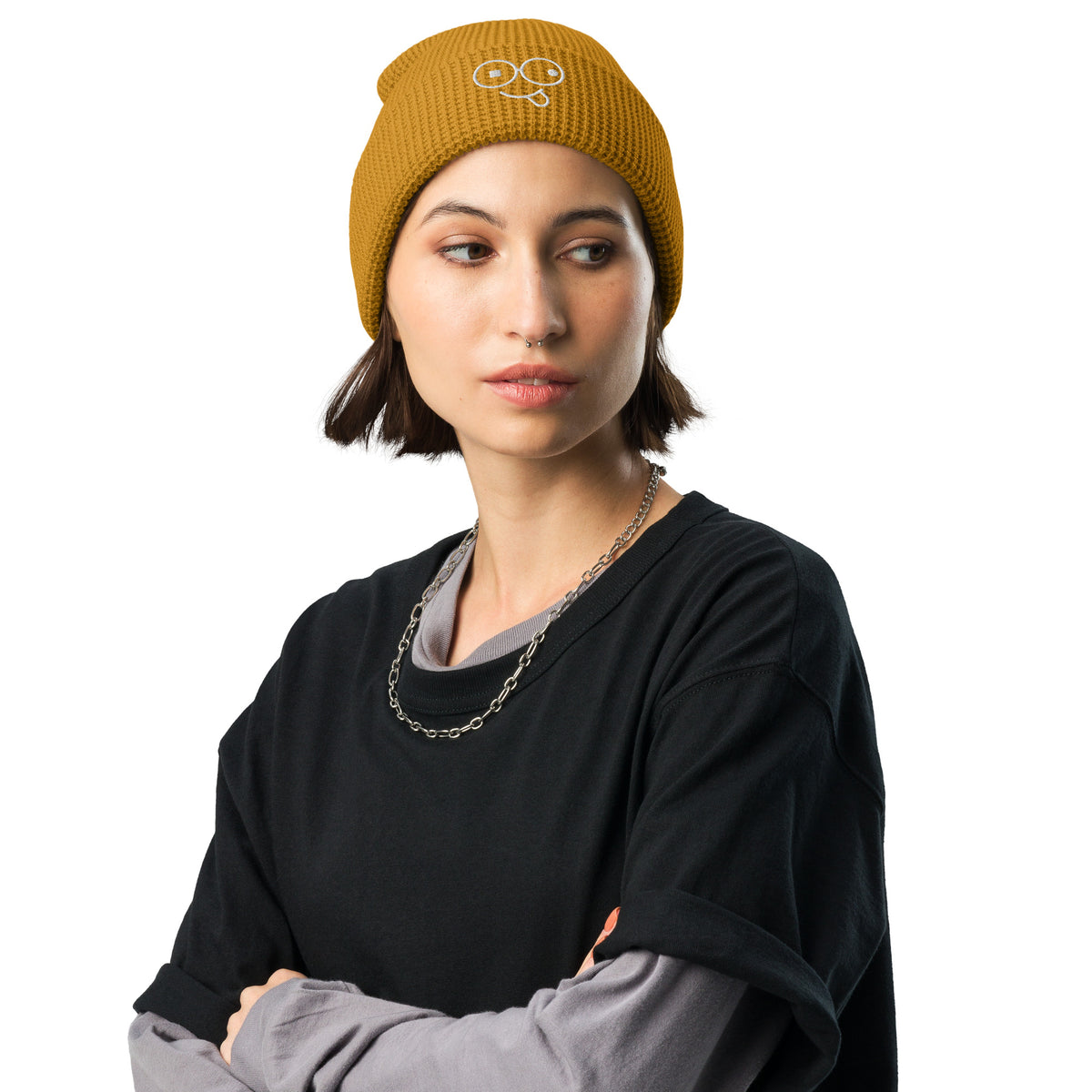 Model wearing a rust waffle knit beanie with a folded cuff and light-colored tongue-out glasses-face design