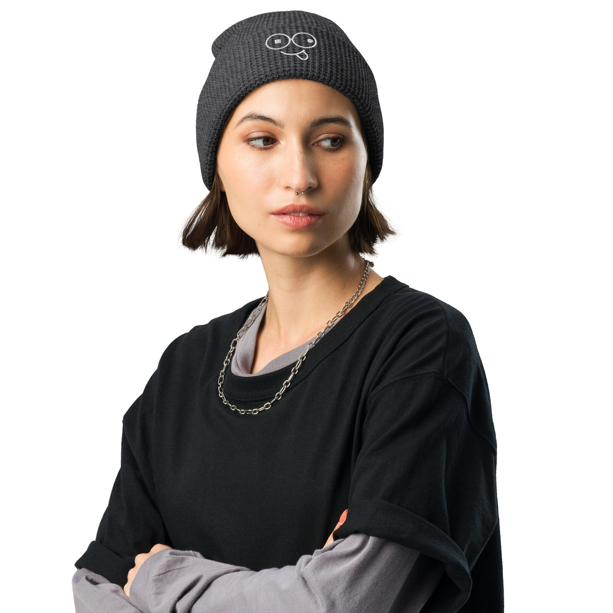 Model wearing a navy waffle knit beanie with a folded cuff and white tongue-out glasses-face design