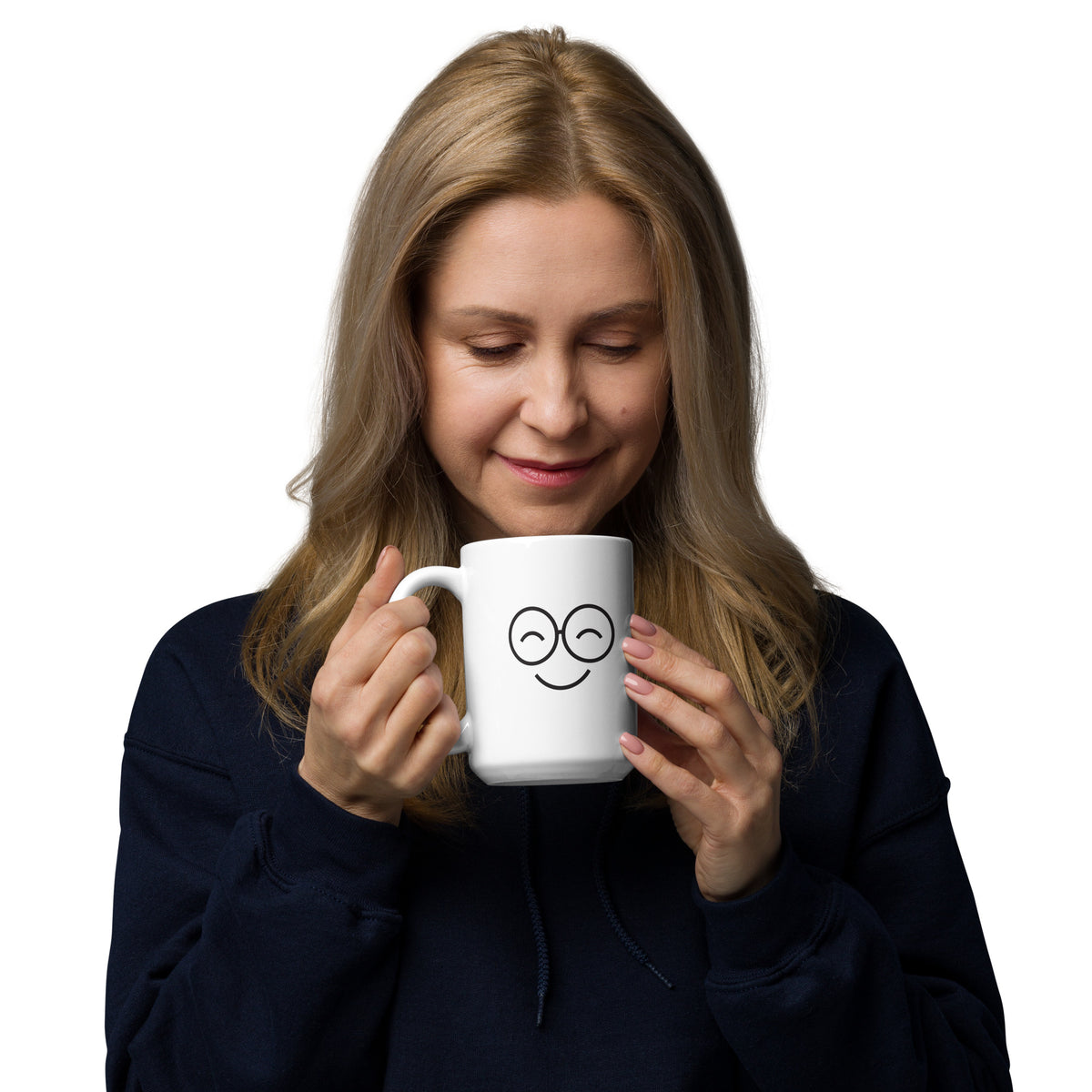 Person looking down at a white mug with black smiling glasses-face artwork and a right-side handle

